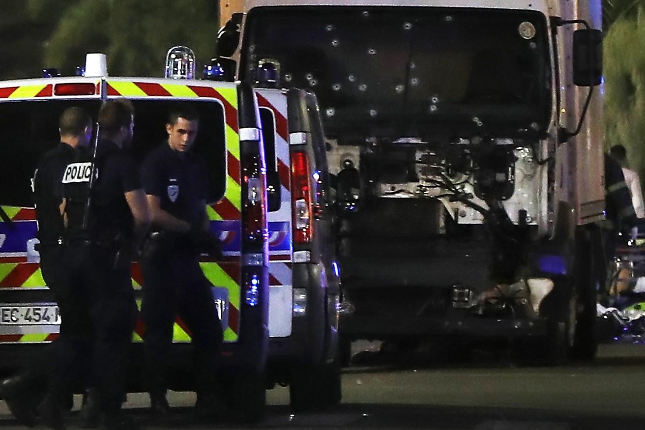 Des policiers se tiennent, le 17 juillet 2016, près du camion précipité sur la foule le soir du 14 juillet à Nice  / AFP
