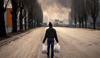 A man walks holding bags near a burning warehouse hit by a Russian shell in the suburbs of Kyiv on Thursday.