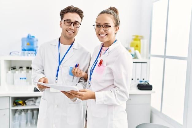 Man and woman wearing scientist uniform working at laboratory