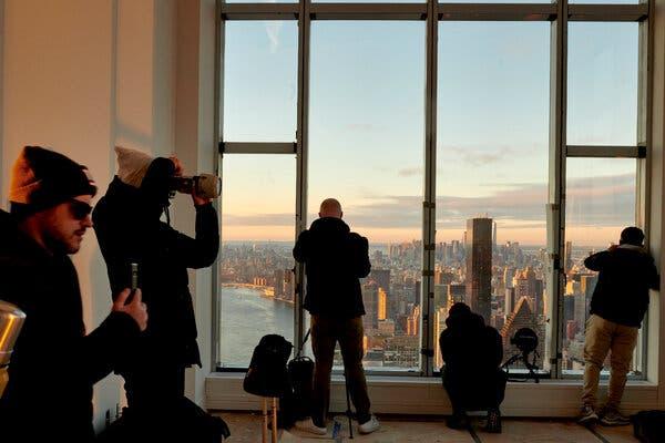 Photographers taking photos of the Manhattan skyline from a window that takes up an entire wall.