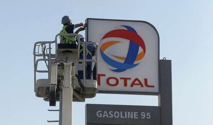 Des ouvriers installent le logo du géant pétrolier               français Total dans une station-service du Caire, en               octobre 2016.