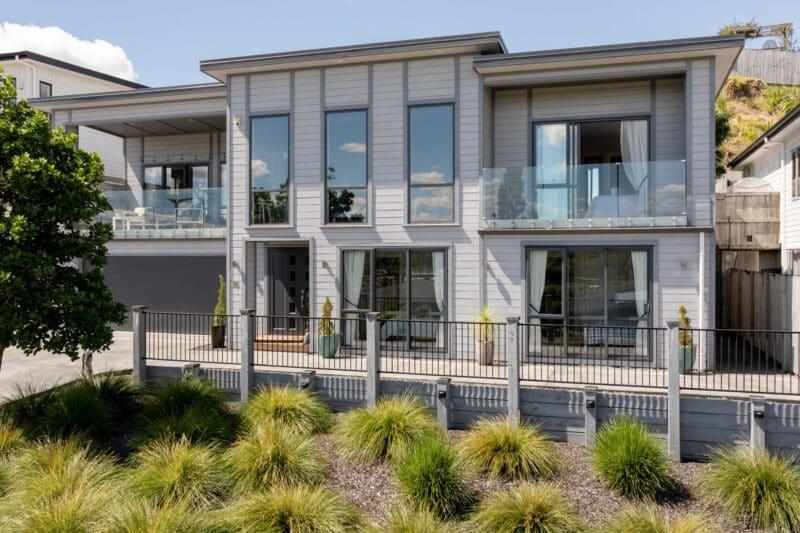 A stylish, single-story home with a modern design, large windows, and a well-kept lawn, listed by The Northern Group, recognized as the Best Real Estate Agent.