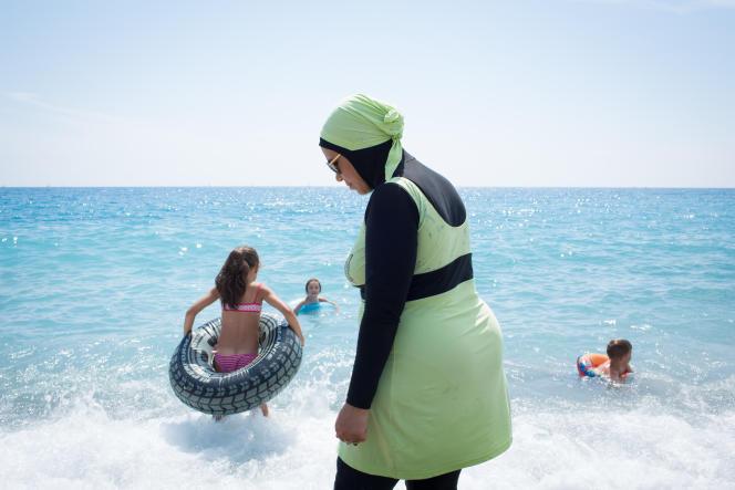 Une jeune maman portant une combinaison intégrale pour se baigner. à Nice le 17 juillet 2016.