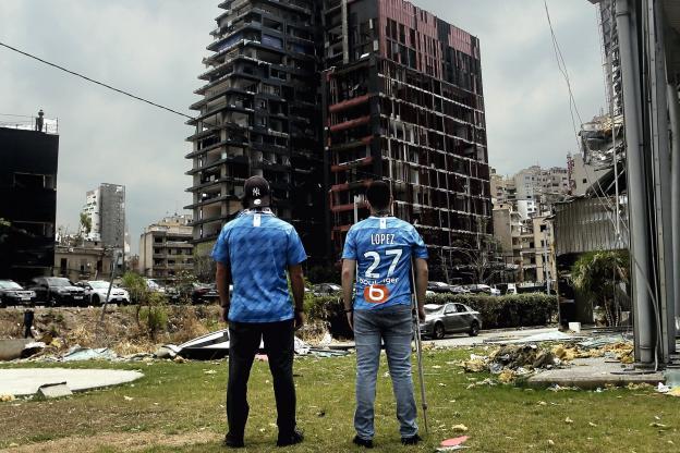 Karim Lahoud, le fondateur de l'OM Nation Beirut, fan-club dont Cyril Canaan faisait partie, et Thierry Gédéon, un membre historique, au pied de la tour Skyline située en face du port et dévastée par l'explosion. (Photo Marwan Naamani/Polaris)
