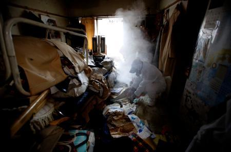 Pracownik specjalnego sprzątania używa środków owadobójczych do zabijania much w mieszkaniu pełnym śmieci w Tokio