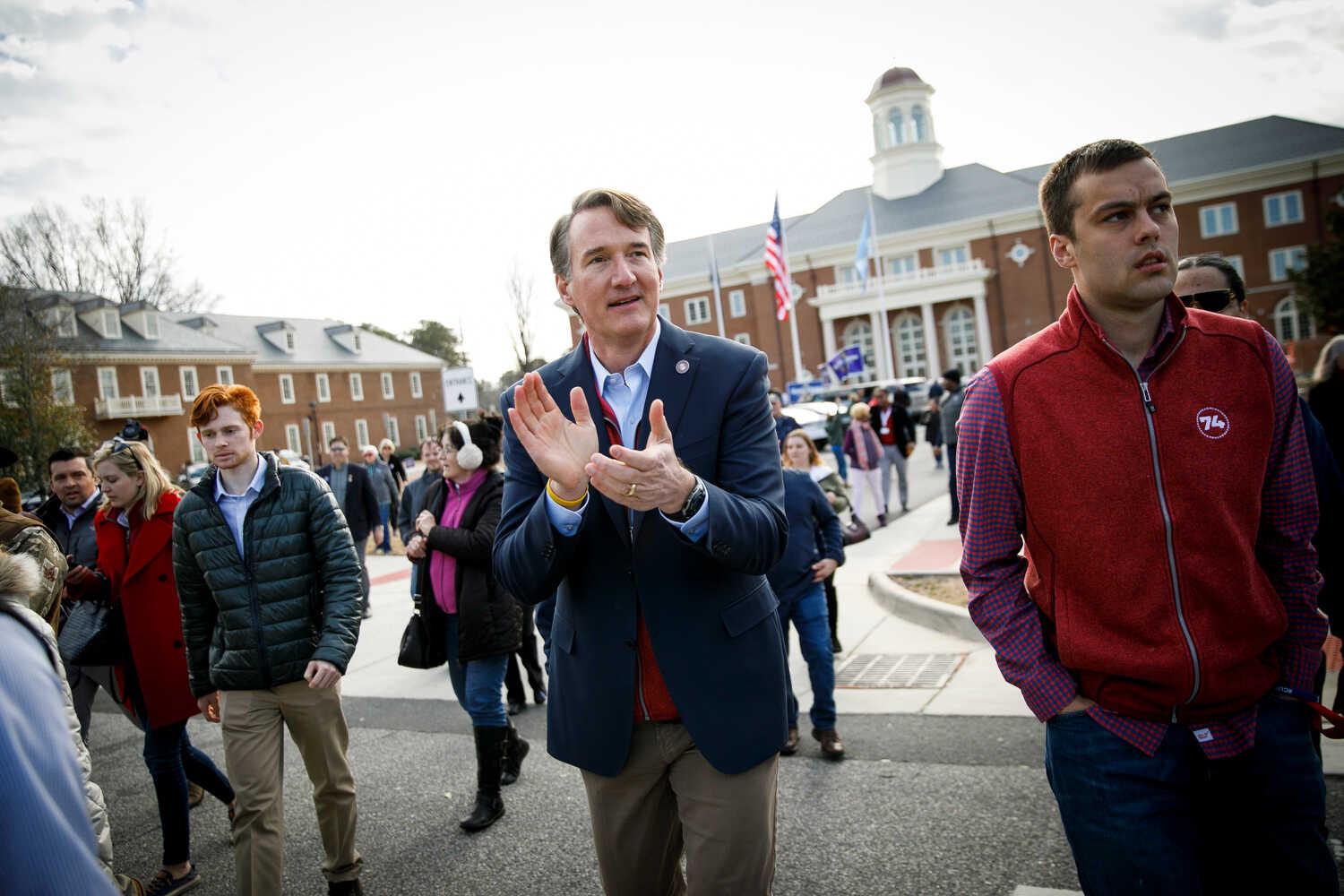 Governor Glenn Youngkin of Virginia in a blue blazer applauds as he walks among supporters in the plaza in front of the Virginia Beach City Hall.