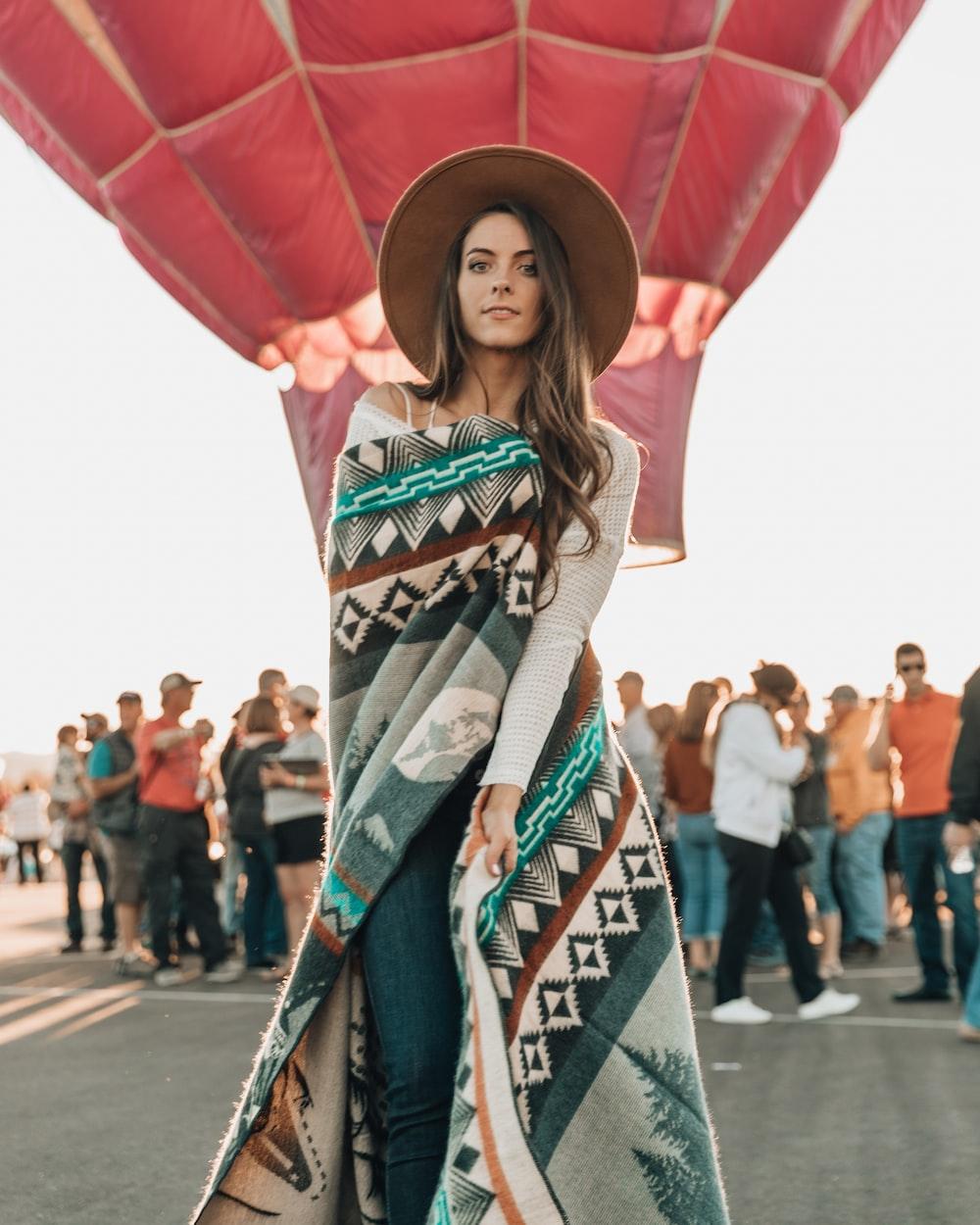 woman wearing brown curved brim cap standing near red hot air balloon