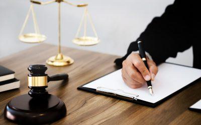 A judge writing on a clipboard with a gavel and scales of justice in the background, symbolizing the role of commercial lawyers in legal matters.