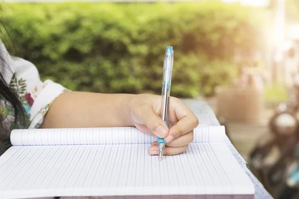 Girl holding pen writing on notebook Stock Image