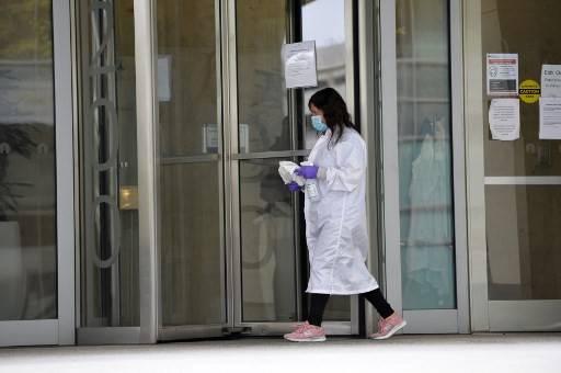A woman cleans the entrance doors to Moderna headquarters in Cambridge, Massachusetts on May 18, 2020.Moderna Inc said on Sunday it has received an additional $472 million from the US government's Biomedical Advanced Research and Development Authority (BARDA) to support development of its novel coronavirus vaccine.
