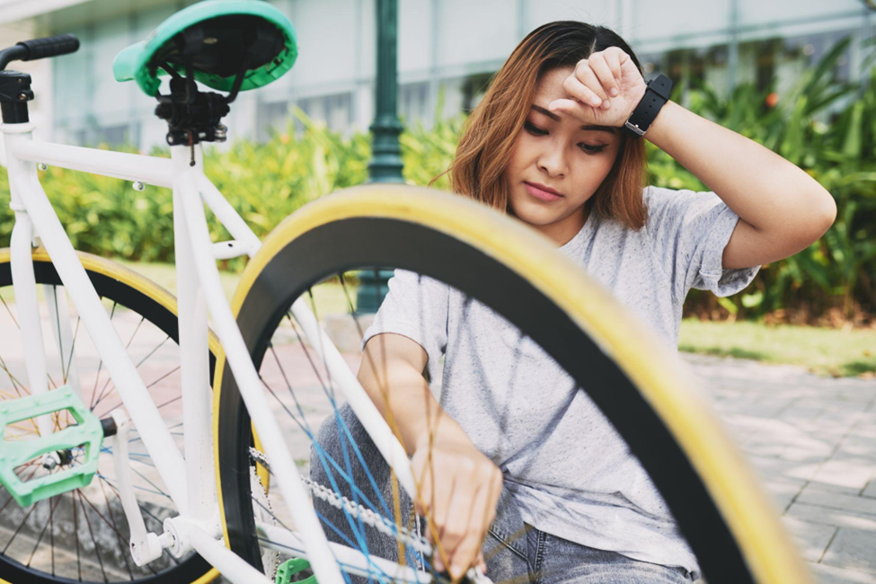 A photo of an exhausted cyclist kneeling next to her traditional bicycle