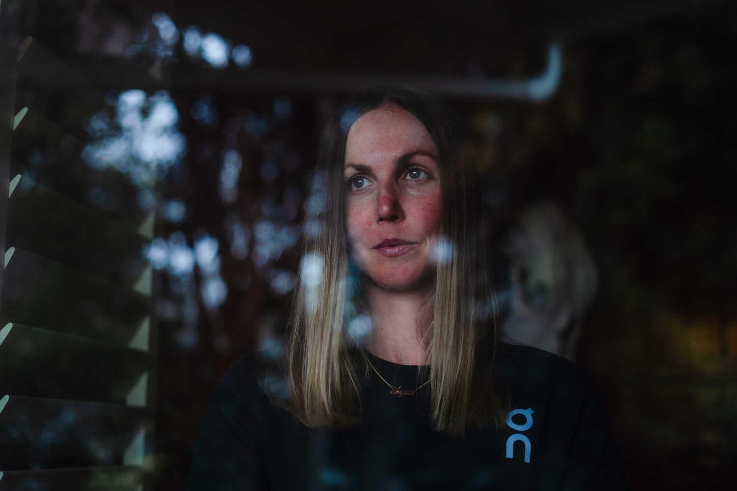A portrait of Chelsea Sodaro, who is photographed through a window.