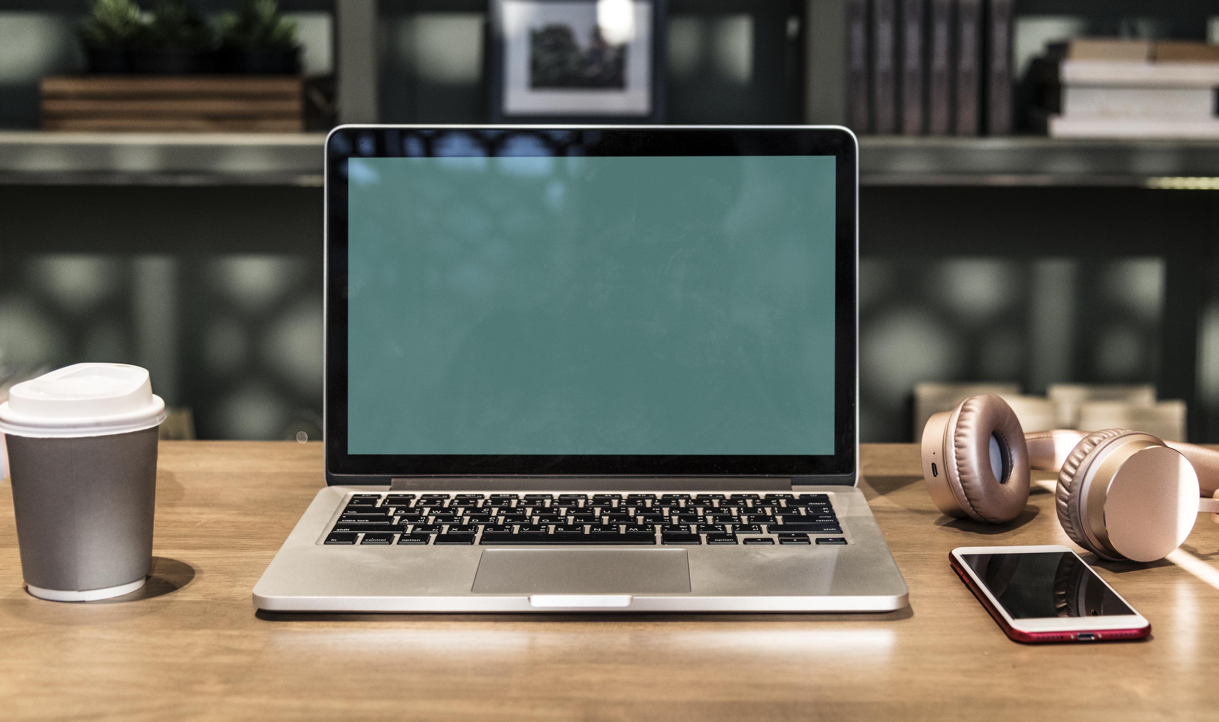 Close-Up Photography of Macbook Near Mobile Phone And Headset