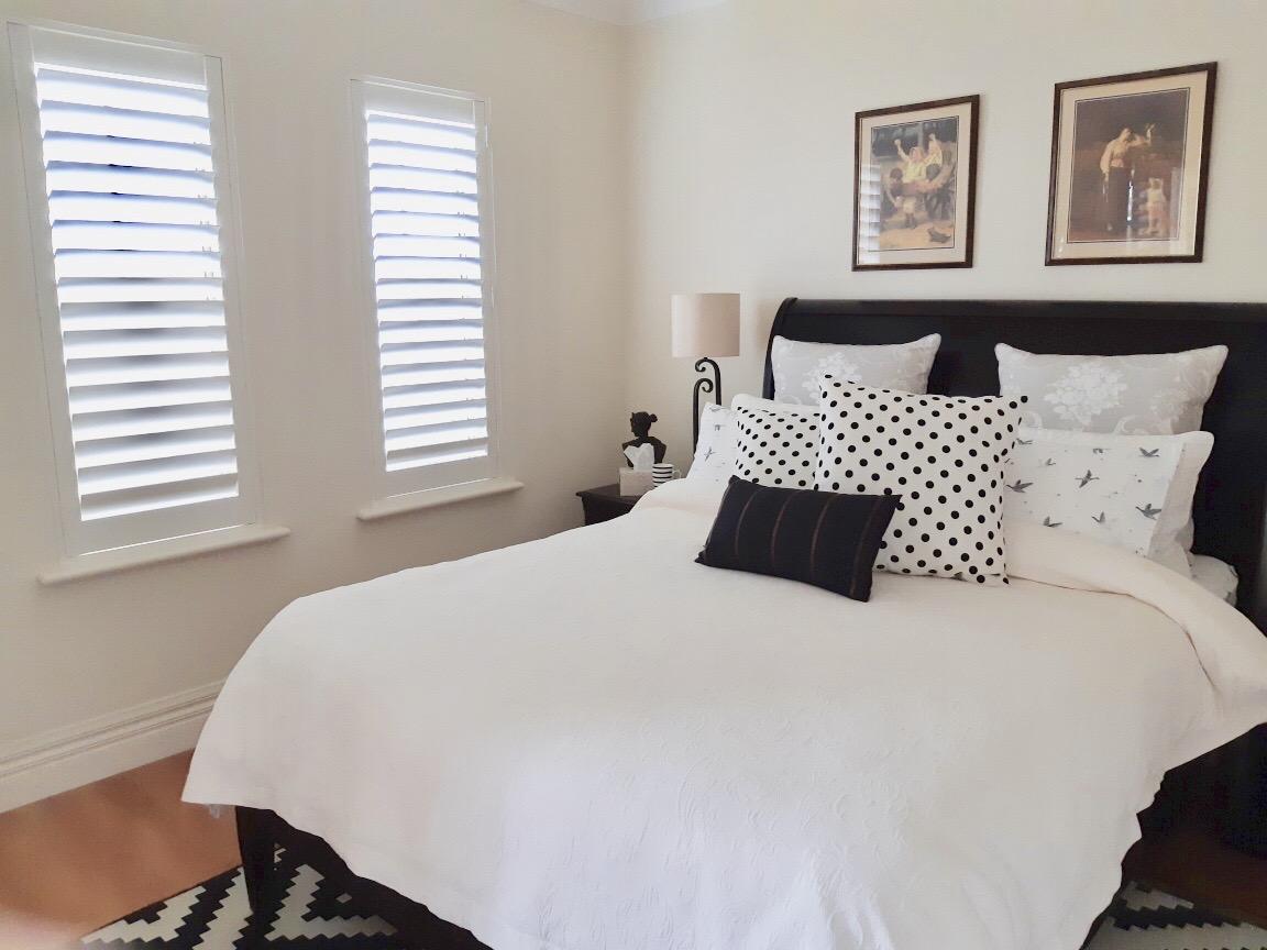 Cozy bedroom with stylish plantation shutters installed by ASI Security in Adelaide, adding privacy and elegance.