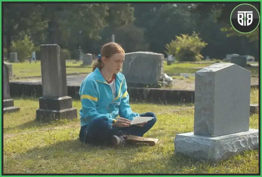 A girl is sitting in front of a stone in stanger things season 4