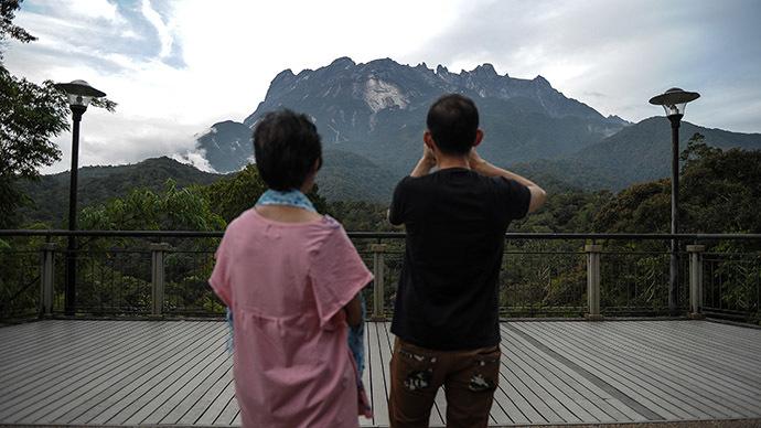 A tourist (R) takes pictures of Malaysia's Mount Kinabalu a day after the earthquake in Kundasang, a town in the district of Ranau on June 6, 2015. (AFP Photo/Mohd Rasfan)