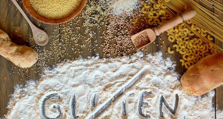 Gluten free cereals corn, rice, buckwheat, quinoa, millet, pasta and flour with scratched text gluten on brown wooden background,overhead horizontal view