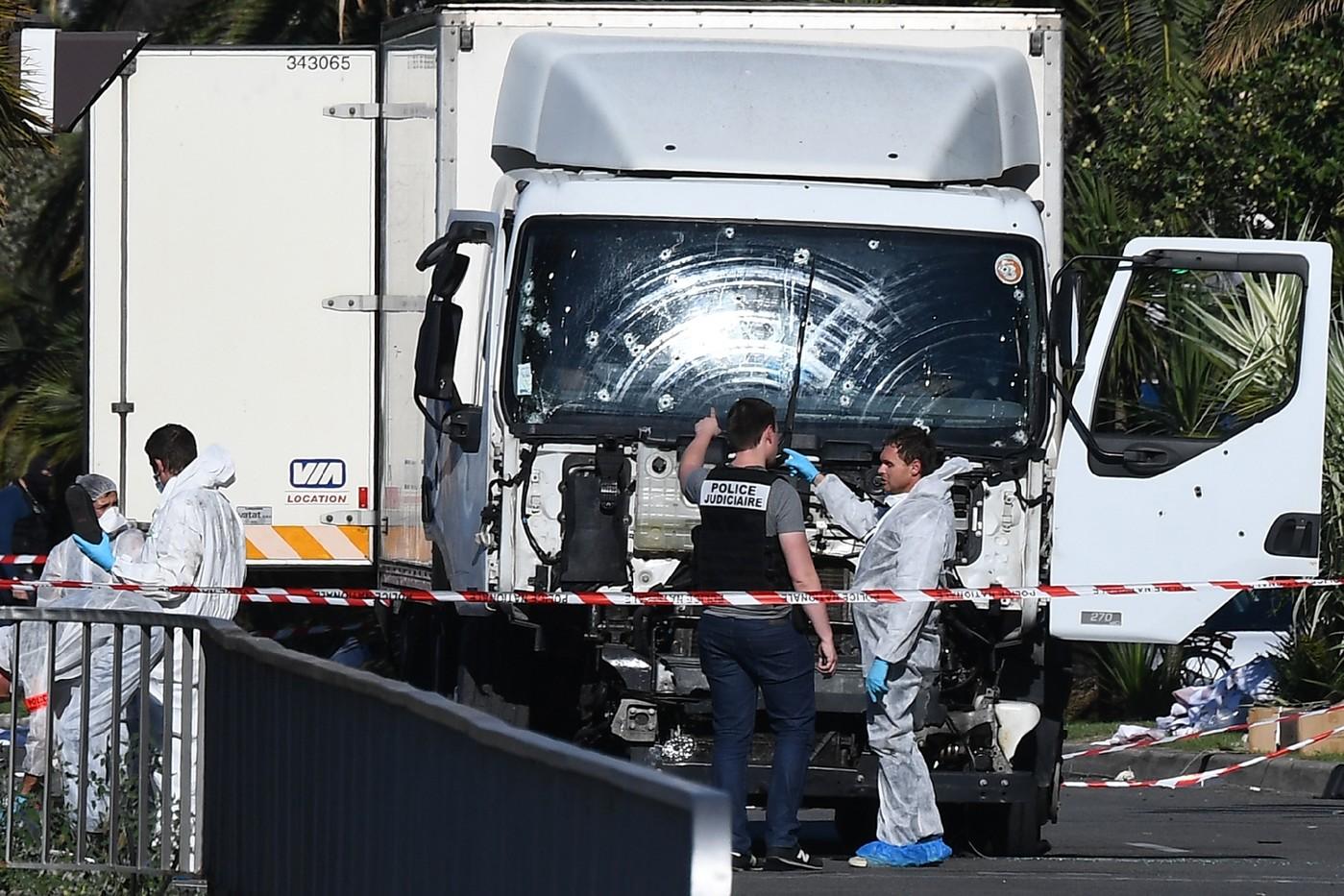 Des experts scientifiques de la police devant le camion criblé de balles de l'auteur de l'attentat sanglant de Nice, le 15 juillet 2016 / AFP