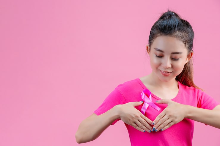 Breast cancer awareness , Woman in pink t-shirt with satin pink ribbon on her chest, supporting symbolbreast cancer awareness