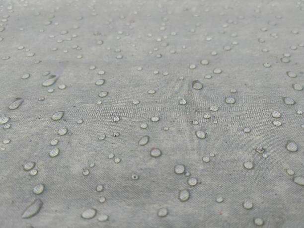 Gray fabric with dew drops Gray fabric with dew drops. Gray water-repellent fabric for furniture or clothing, with moisture drops. Artificial surface. Modern nano-leather or eco-leather. Textured background or backdrop. nano waterproofing stock pictures, royalty-free photos & images