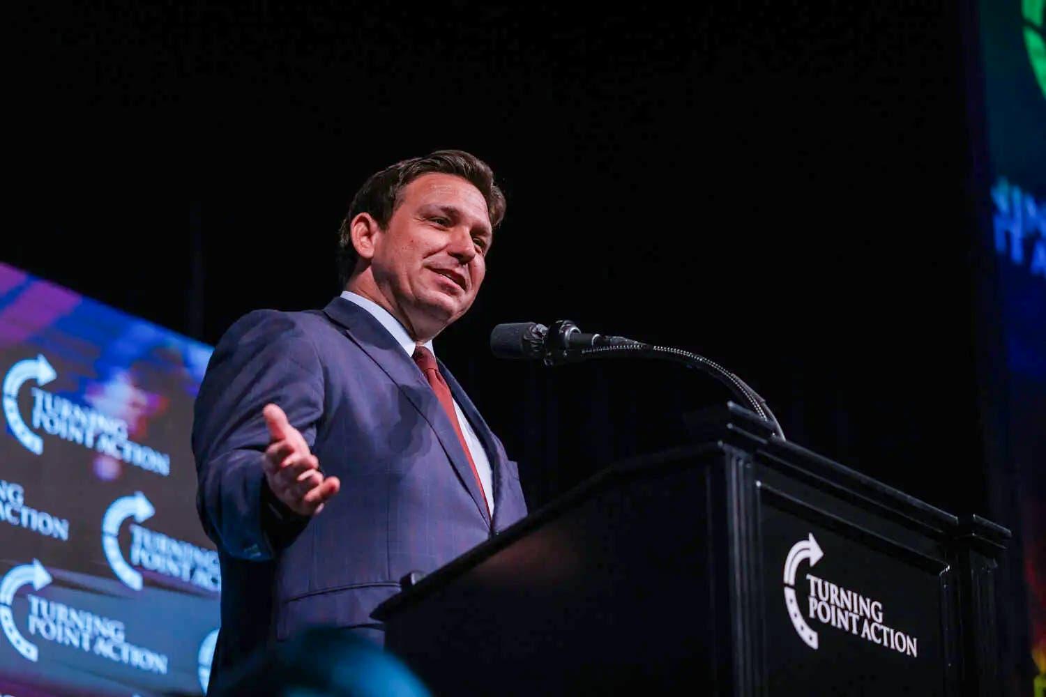 Gov. Ron DeSantis of Florida gesturing with his arms as he speaks at a lectern.