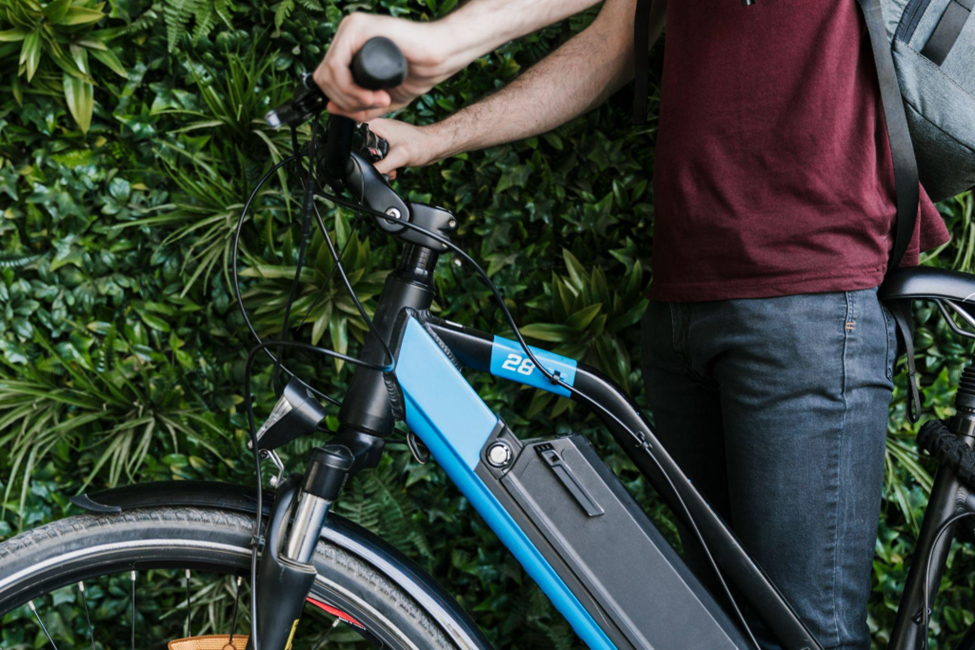 A photo of a cyclist standing next to an electric bicycle