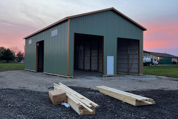 This may contain: two wooden benches sitting in front of a green building with a pink sky behind it