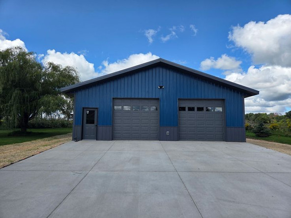 This may contain: a blue building with two garages and trees in the background