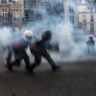 Police officers run through smoke of tear gas during a protest against the 'global security' draft law, which Article 24 would criminalise the publication of images of on-duty police officers with the intent of harming their 'physical or psychological integrity', in Paris, on November 28, 2020. Dozens of rallies are planned on November 28 against a new French law that would restrict sharing images of police, only days after the country was shaken by footage showing officers beating and racially abusing a black man. (Photo by Ameer AL-HALBI / AFP)