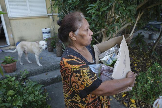 Claudia, 61 ans, habitante du quartier « Rivière salée », porte de la nourriture distribuée par les bénévoles de l’association caritative « Solidarite RS » à Nouméa, le 6 juin 2024.