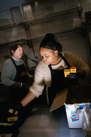 Des bénévoles préparent les plateaux distribués aux bénéficiaires, au restaurant solidaire de la Food Bank NYC à Harlem, à New York, le 3 décembre 2025.