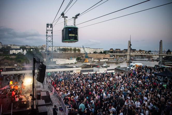 Le téléphérique urbain de Brest (Finistère) passe au-dessus de la Penfeld, le fleuve qui traverse la ville, et de la foule massée sur l’esplanade Césaria-Evora, lors d’une fête, le 28 juin 2024.
