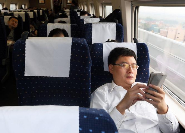Un passager regarde son téléphone portable, installé dans un TGV entre Pékin et Guangzhou, en décembre 2012.