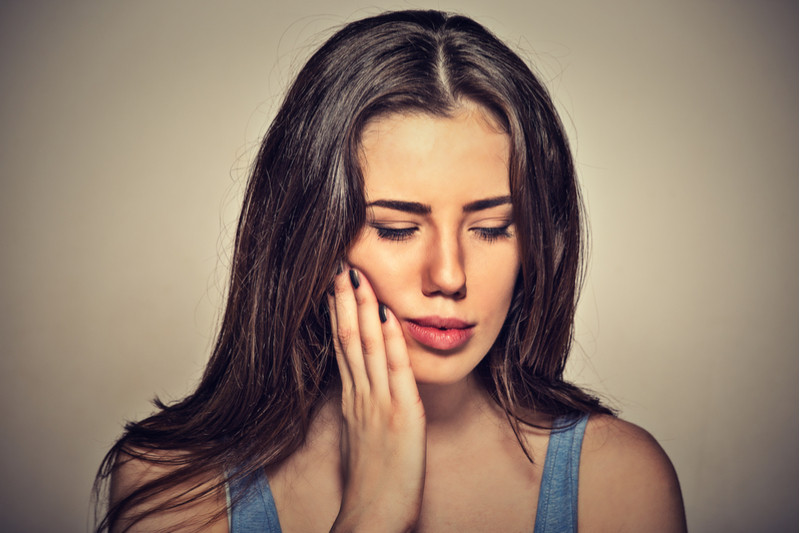 A woman experiencing pain from her wisdom teeth and needing a dental appointment for wisdom teeth removal.