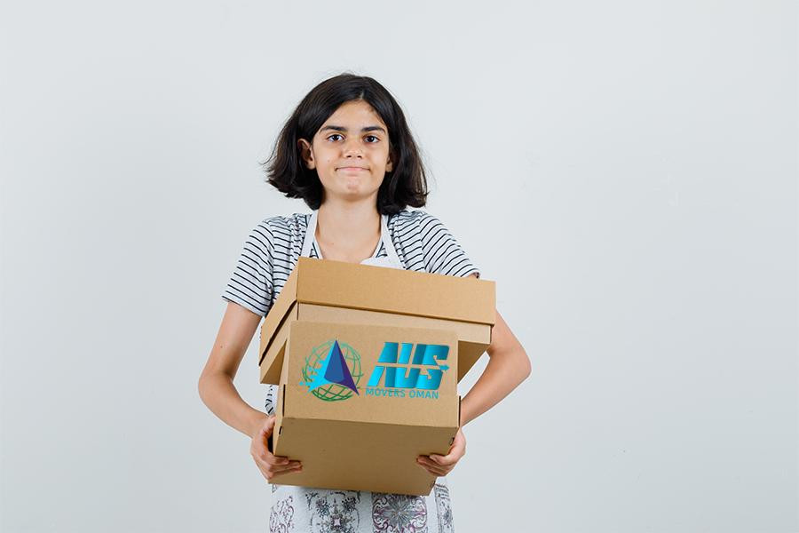 A young person holding stacked cardboard boxes, representing a stress-free move with Muscat movers and packers from AUS Movers and Logistics in Muscat, Oman.