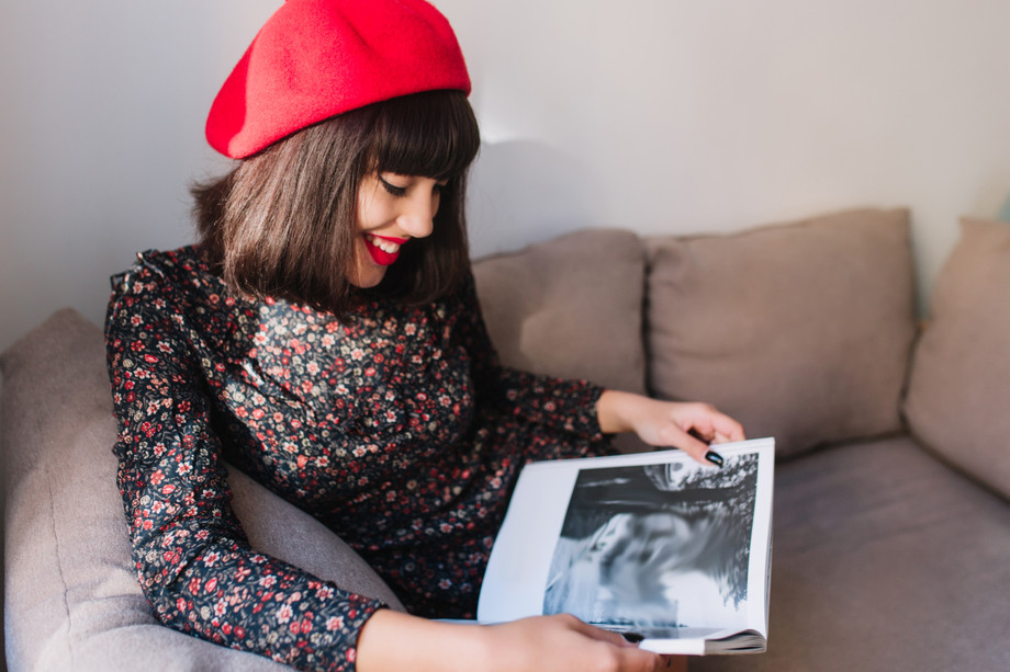 stylishspectaculargirlredberetlookswithinterestphotobookleaningherelbowsgraysofaportraitcharmingyoungfrenchwomanvintageclothesreadingmagazinefreetime.jpg