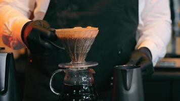 8888888__llcropviewofbaristahandsinblackglovesmakingpouroveronwoodentablecloseupviewofbartendermalehandspouringhotwaterontocoffeegroundstomakepourerconceptofcoffeepreparationvideo.jpg