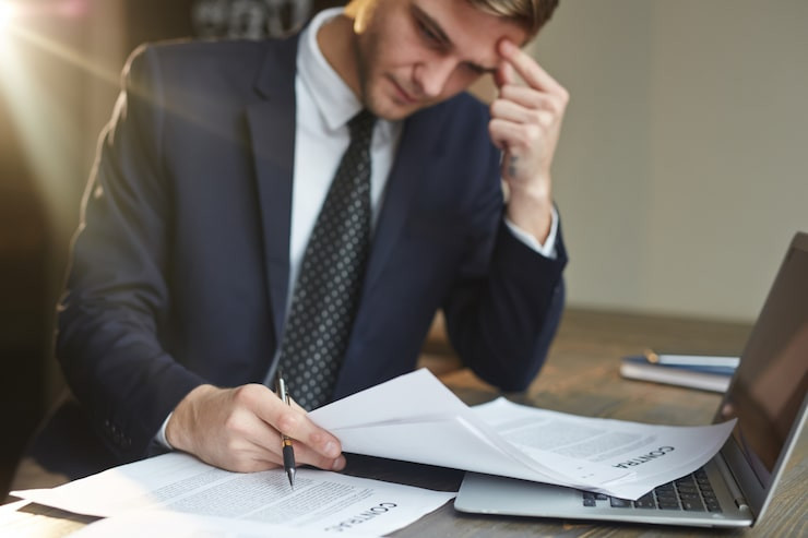 stressedbusinessmanworkingwithcontractdocuments_109815392.jpg