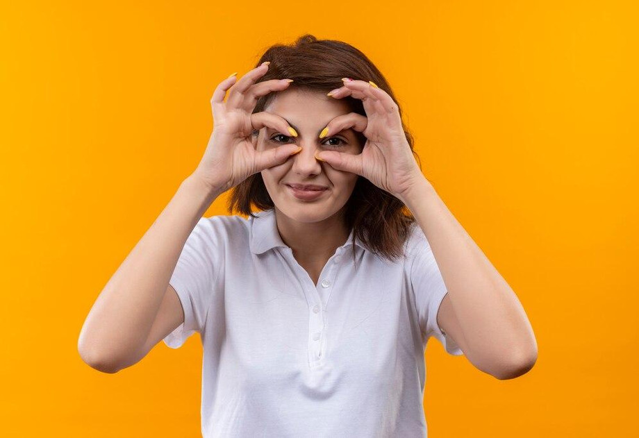 younggirlwithshorthairwearingwhitepoloshirtmakingoksignswithfingerslikebinocularslookingthroughfingerssmiling_14179346503.jpg