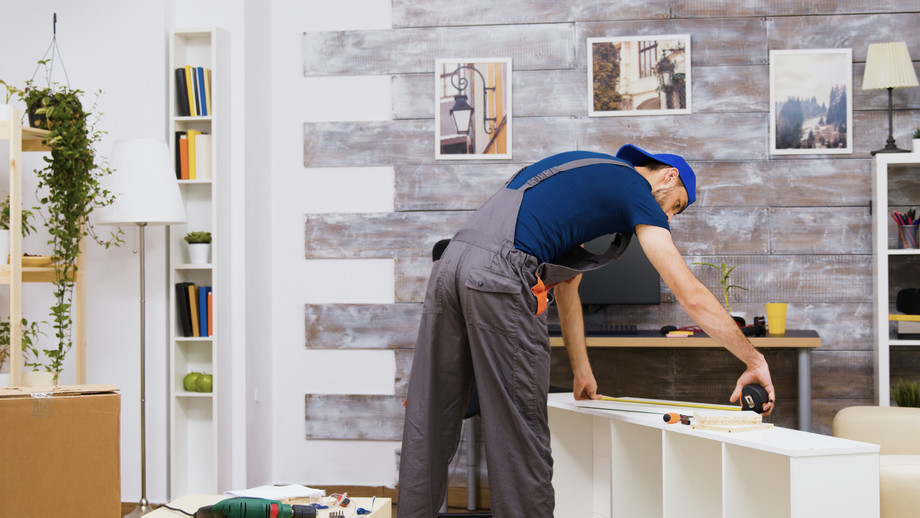 furnitureassemblyworkerstandingreadinginstructionusingtapemeasureworkertools.jpg