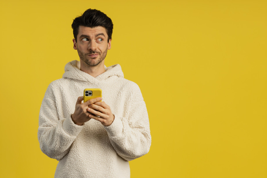 frontviewmanlookingmischievouswhileholdingsmartphone.jpg