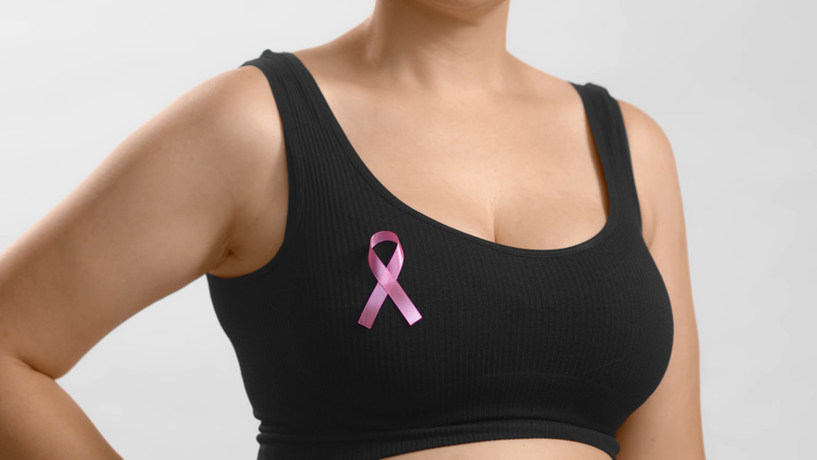 youngeuropeanladyblacktopstandingwithribbonsignherchestsupportpinkoctoberfemalescombatingbreastcanceranonymousstudioshothighqualityphotowhitebackground.jpg