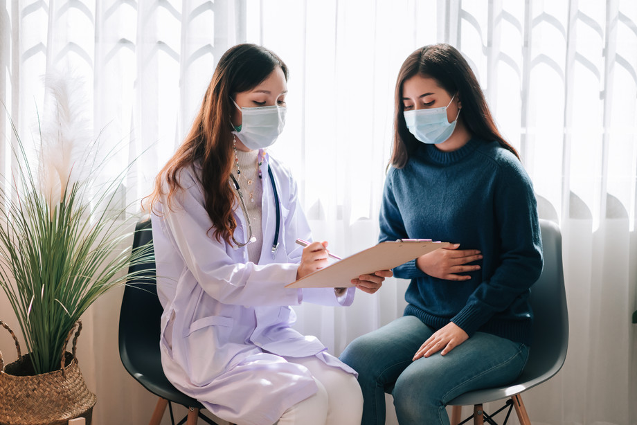 asiandoctorvisitexaminesyoungadultwomanhospitalwithstomachachedoctorcheckingupconsultinghealthcarewearingmaskprotectcovid19pandemic1.jpg